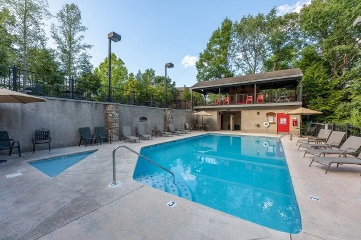 A vibrant exterior shot of the resort's swimming pool and hot tub area, surrounded by lounge chairs and an outdoor bar. The space feels lively and social, suggesting opportunities for relaxation, family fun, and community interaction after a day of exploring nearby attractions.