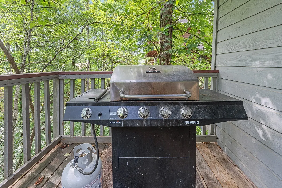 A close-up of a grill set beside abundant natural greenery, ready for outdoor barbecuing. The setting suggests a casual, social environment perfect for summer cookouts and entertaining guests.