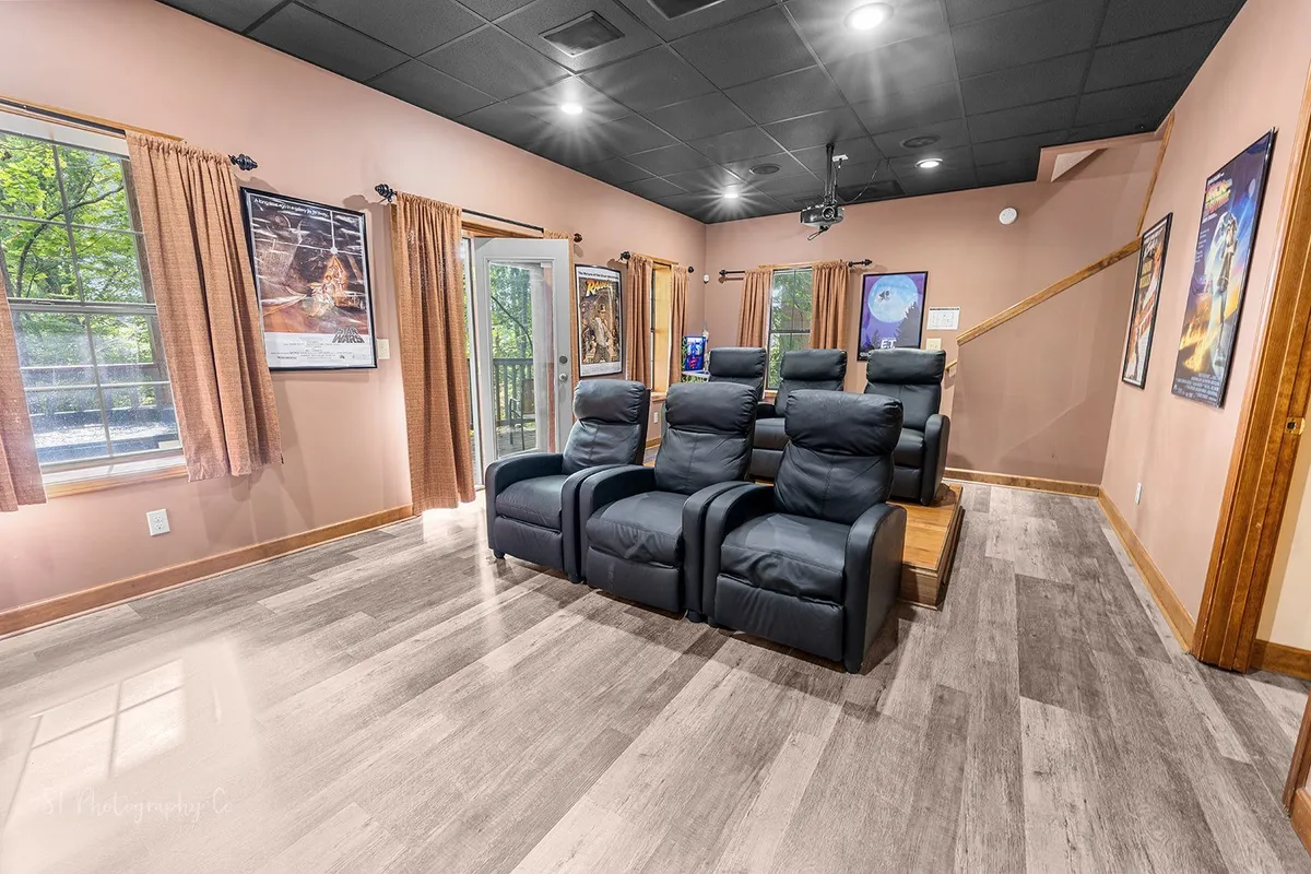 A cozy theatre room featuring multiple reclining chairs arranged before a large screen, with movie posters and natural light from the windows. The space is designed for immersive viewing experiences, perfect for movie nights or watching the big game. The relaxed mood is ideal for unwinding after energetic play.