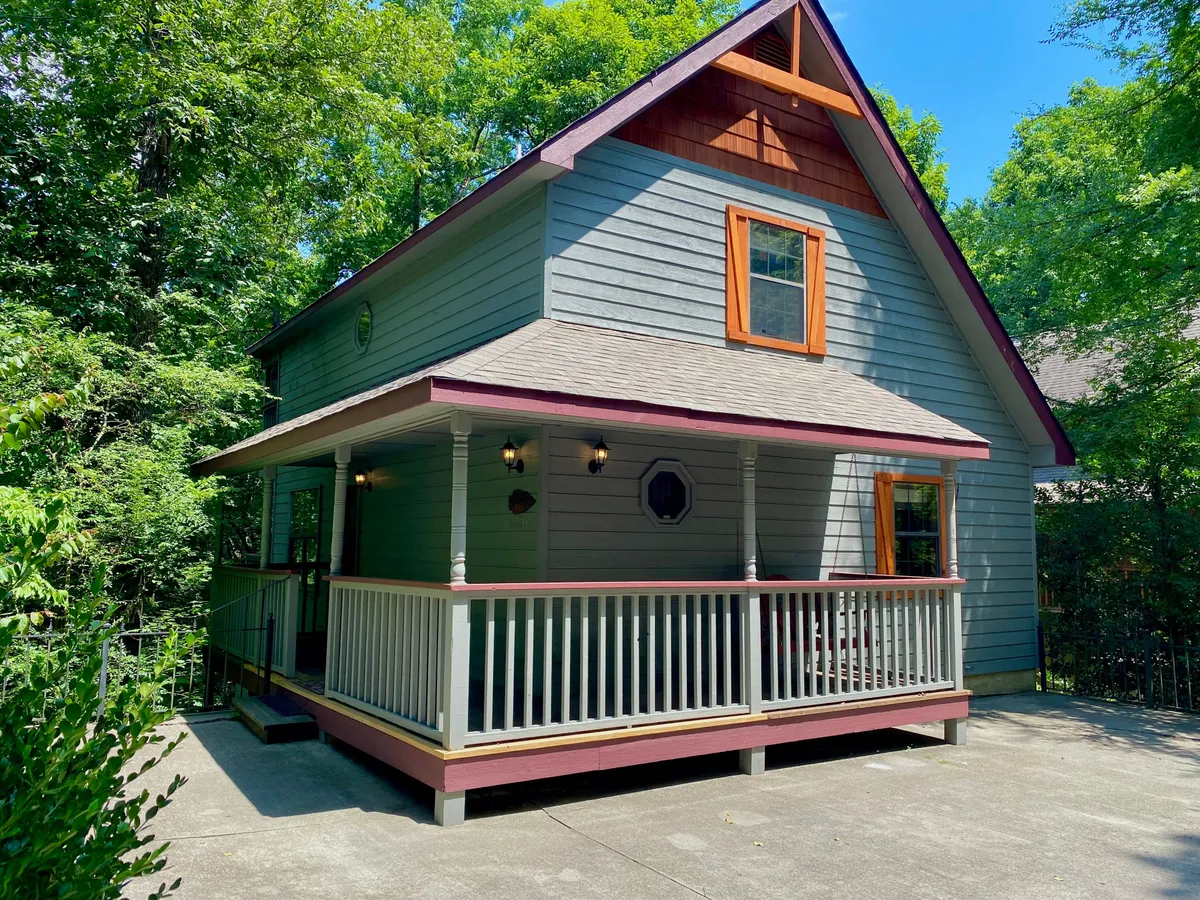 This image presents an exterior view of the front porch with decorative windows and a charming roof design. It suggests a welcoming entry and a cozy spot for gatherings or simply relaxing while taking in the natural surroundings.