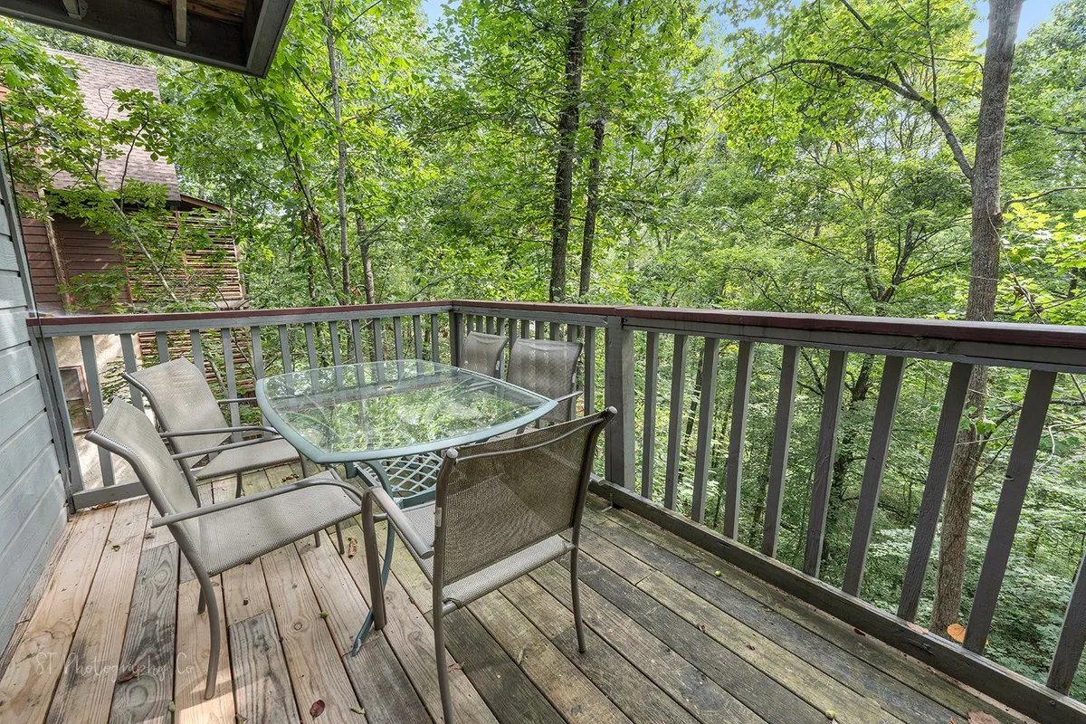 This image captures a serene outdoor dining area with a glass table and chairs set amidst surrounding trees. The scene exudes a tranquil, communal atmosphere ideal for group meals or morning coffee while soaking in the fresh mountain air. The lush greenery and natural light highlight the retreat's connection to nature, reinforcing its suitability for gatherings.