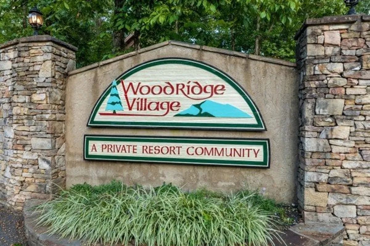 This exterior scene showcases welcoming signage set between stone pillars and well-maintained landscaping, inviting guests to explore the broader resort community and its natural surroundings.